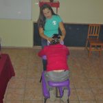 Masajistas realiza un masaje a silla a un profesor empezando por el cuello